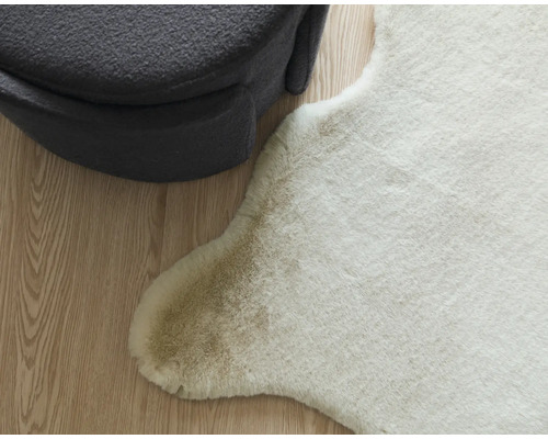 Imitation décorative de peau de bête à côté d''un pouf gris sur un plancher en bois.