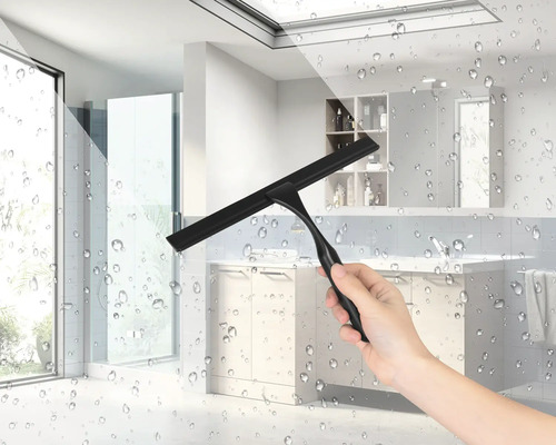 Une main tient une raclette de douche noire dans une salle de bains.