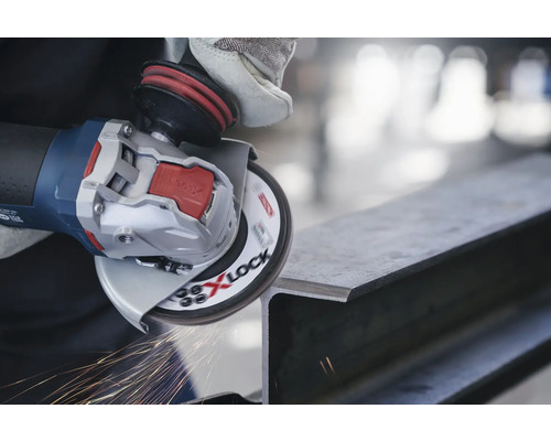 Une meuleuse angulaire avec X-Lock meule une pièce de métal, produisant des étincelles.