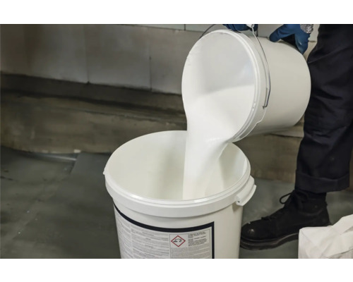 Person giesst weisse Farbe in Eimer