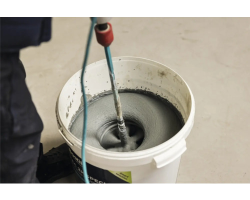 Mörtel wird mit einem Rührwerk in einem Eimer gemischt.