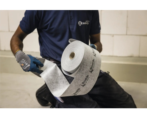 Eine Person hält eine Rolle Bostik-Entkopplungsmatte