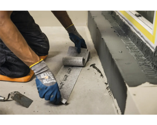 Handwerker verlegt Dichtband zur Abdichtung im Badezimmer