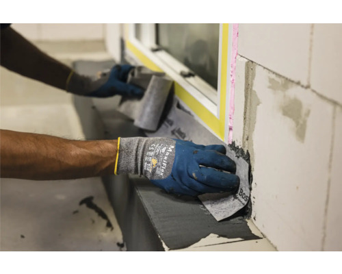 Handwerker bringt Dichtungsband an Fenster an