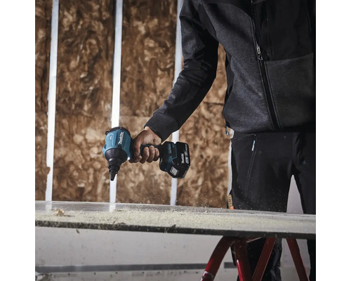 Une personne utilise une visseuse à plaques de plâtre sans fil Makita pour visser une plaque de plâtre.