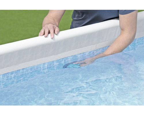 Un homme nettoie une piscine avec une épuisette de fond