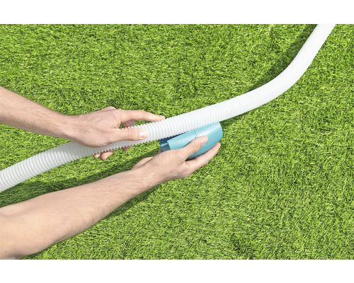 Personne raccordant un tuyau de piscine à un appareil de nettoyage sur une pelouse