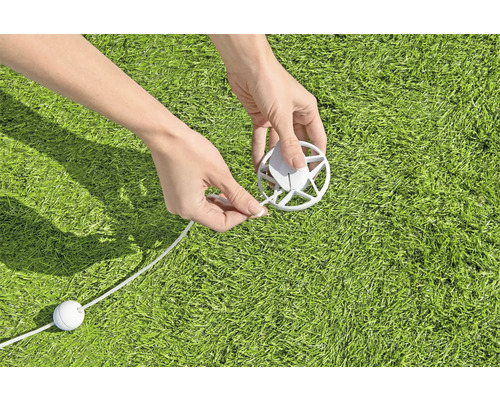 Une personne fixe une ligne à une couverture sur une pelouse