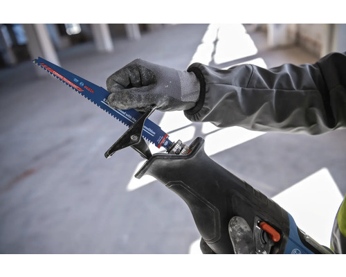 Une personne insère une lame de scie sabre dans une scie sabre.