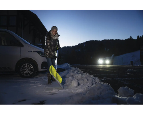 Femme pelletant la neige avec une pelle à neige à côté d''une voiture.