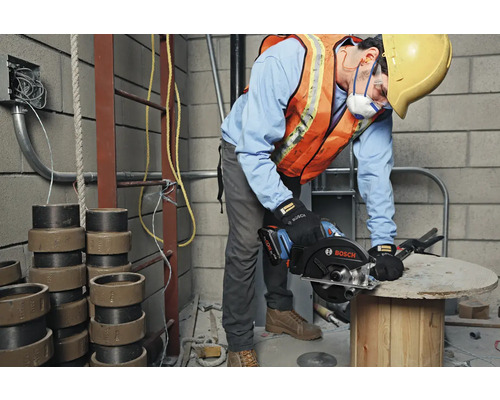 Un ouvrier du bâtiment utilise une scie circulaire portative Bosch sur un chantier.