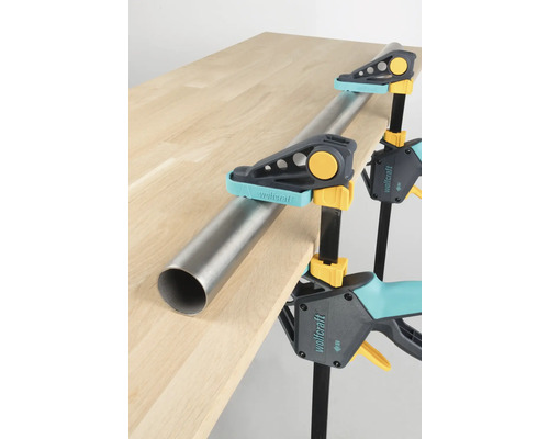 Serre-tubes maintenant un tube métallique sur une table en bois