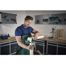 Un homme utilise un serre-joint dans un atelier pour assembler du bois