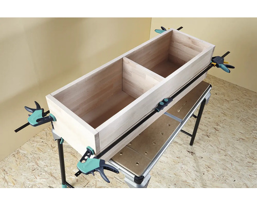 Caisse en bois fixée sur un établi avec des serre-joints