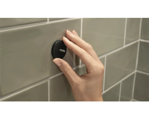 Hand befestigt Wandhaken an Fliesen