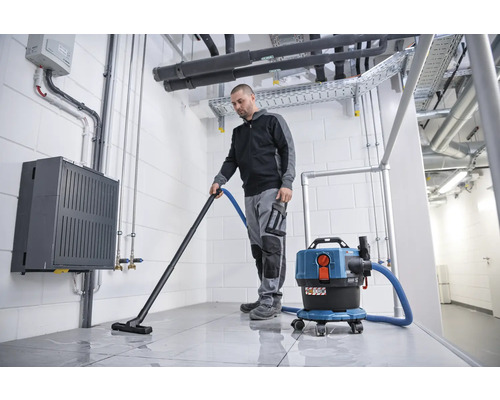 Mann saugt mit einem Nass- und Trockensauger einen Raum
