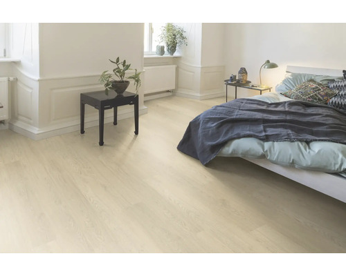 Chambre avec sol stratifié en bois clair, lit et table de chevet