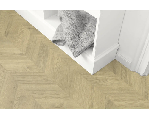 Parquet en bois clair à chevrons à côté d''une étagère blanche avec une couverture