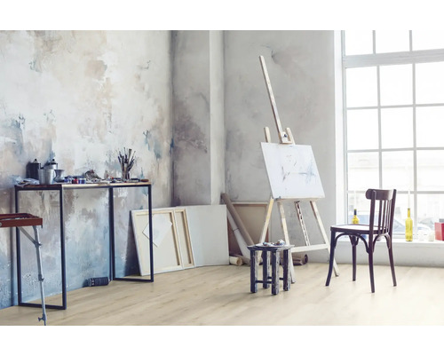 Pièce lumineuse avec chevalet, table avec matériel de peinture et plancher en bois