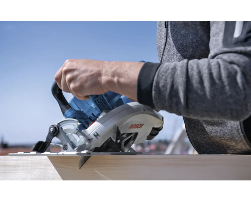 Eine Person schneidet ein Holzbrett mit einer Bosch Tauchsäge.