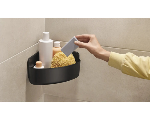 Ecke mit schwarzem Duschregal, gefüllt mit Badprodukten und einem Badeschwamm