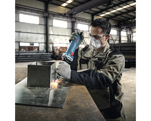 Ein Arbeiter verwendet eine Schleifmaschine zum Bearbeiten von Metall in einer Werkstatt.