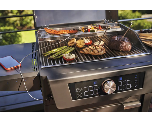 Barbecue avec des aliments comme des légumes, de la viande et un smartphone pour le contrôle de la température