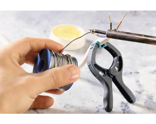 Soudure d''un câble électrique avec de l''étain à souder, de la graisse à souder et une pince.