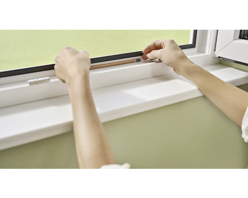 Une personne mesure avec un crayon le joint d''une fenêtre.