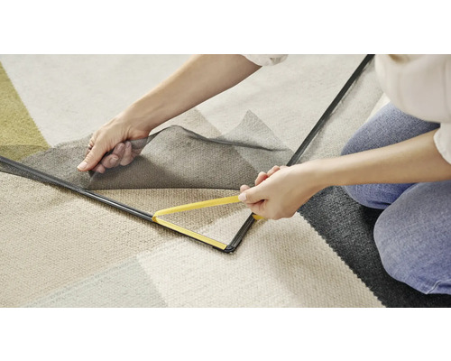 Une femme fixe un cadre de protection contre les insectes à un cadre de fenêtre avec un outil