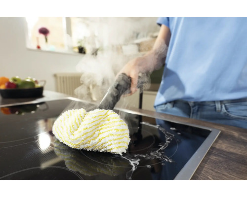 Eine Person reinigt ein Kochfeld mit einem Dampfreiniger.