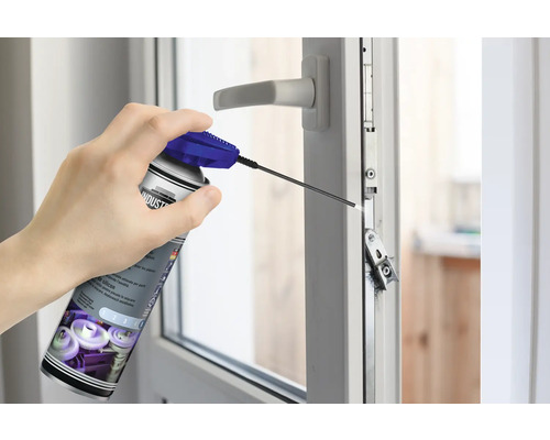 Eine Person sprüht Silikonspray auf ein Fenster