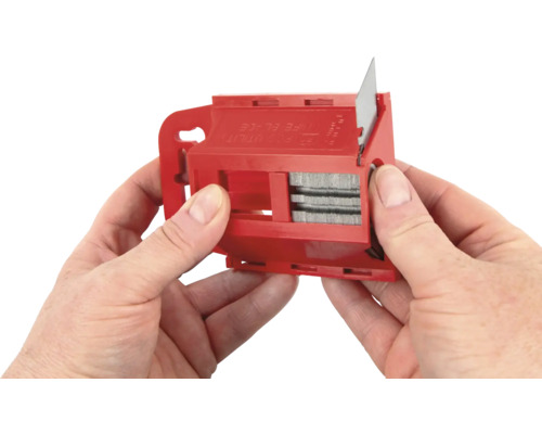 Hände halten einen roten Klingenwechsler für ein Cuttermesser.