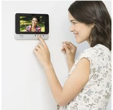 Femme utilisant un interphone de porte Philips au mur