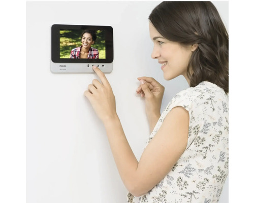 Femme utilisant un interphone de porte Philips au mur