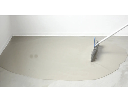 Ausgleichsmasse wird mit einer Rakel auf dem Boden verteilt.