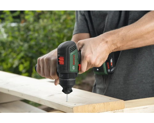Un homme visse une vis dans une planche de bois avec une visseuse sans fil Bosch