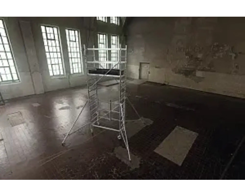 Gerüst in einem leeren Raum mit großen Fenstern für Bauarbeiten.