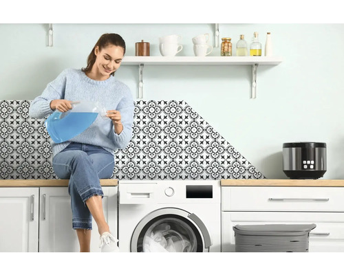Femme assise sur une machine à laver versant du liquide d''un pichet dans un verre doseur