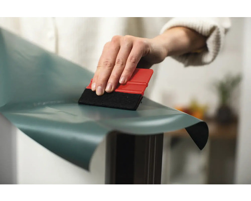 Person bringt eine Dekorfolie mit einem Rakel an