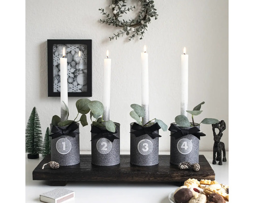 Dekoratives Adventsgesteck mit vier Kerzen, verziert mit Bändern und Eukalyptusblättern auf einem Holztablett