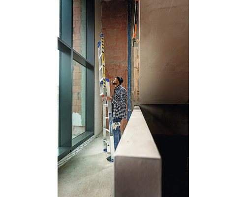 Mann mit Aluminium Mehrzweckleiter in einem Rohbau