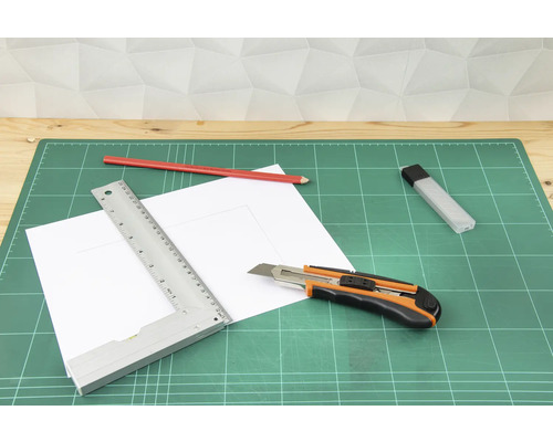 Schneidunterlage mit Cutter, Lineal, Bleistift und Papier