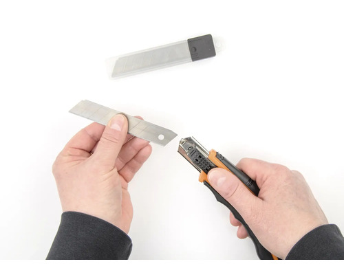 Hände wechseln Klinge an einem Teppichmesser