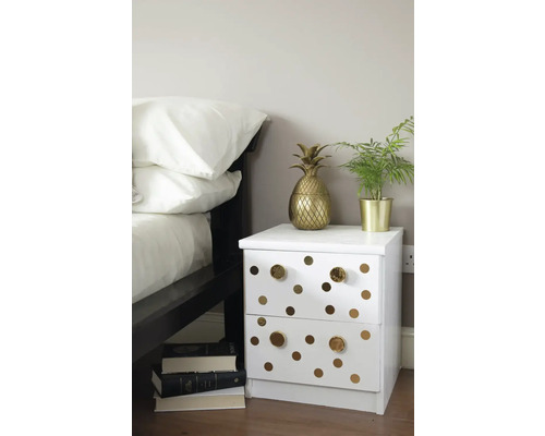 Table de chevet avec deux tiroirs, points dorés et poignées dorées à côté d''un lit