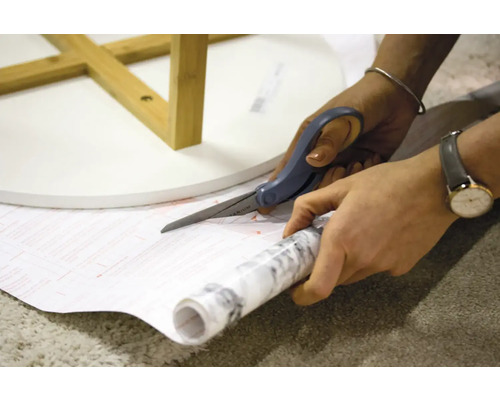 Zuschneiden von Dekorfolie mit einer Schere für einen Tisch