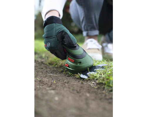 Eine Person benutzt eine Akku-Grasschere von Bosch, um Rasenkanten zu schneiden.