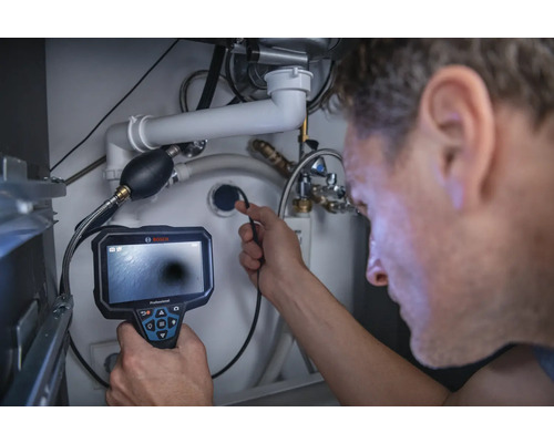 Un homme utilise une caméra d'inspection sous un lavabo pour inspecter les tuyaux.