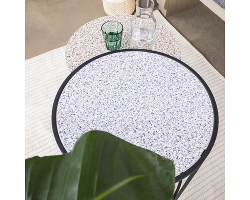 Deux tables d''appoint rondes avec plateaux en terrazzo, un verre et une carafe.