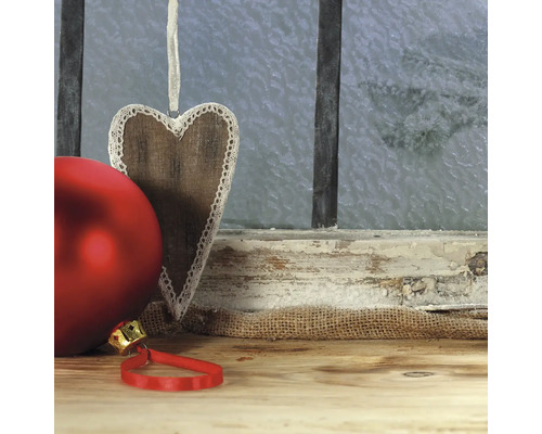 Dekorative Weihnachtskugeln und ein Holzherz vor einem Fenster